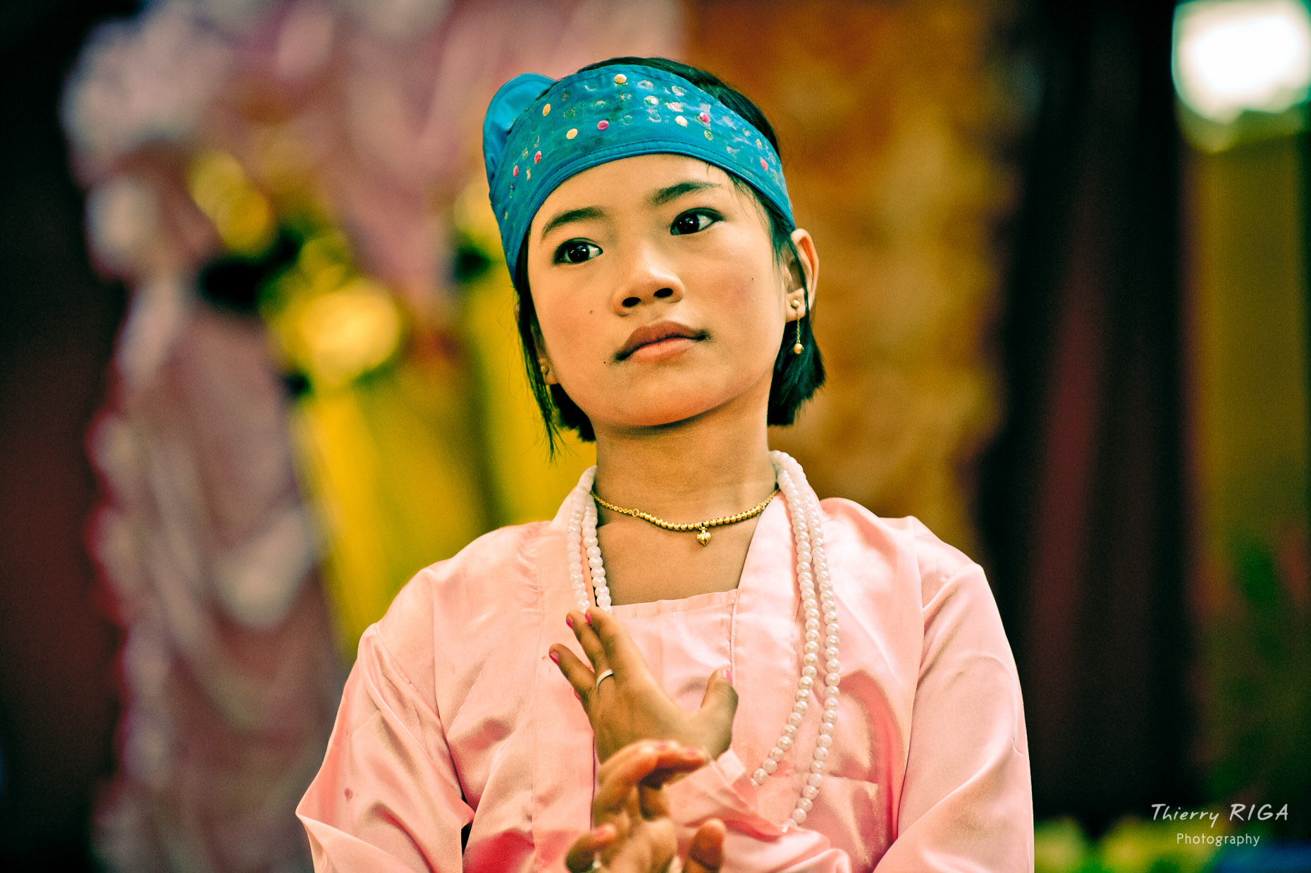 young girl in pink silk dress dancing during buddhist novice ordination ceremony in Bagan, Myanmar