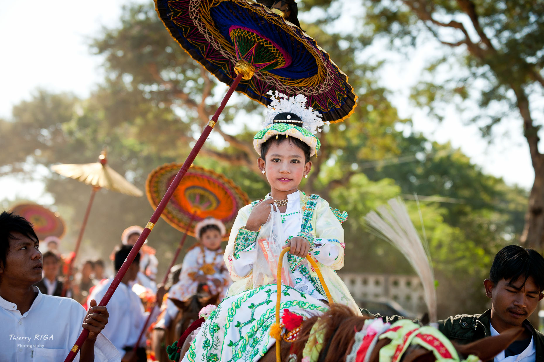 young novice riding a horse under an umbrella during is ordination ceremony, Bagan, Myanmar