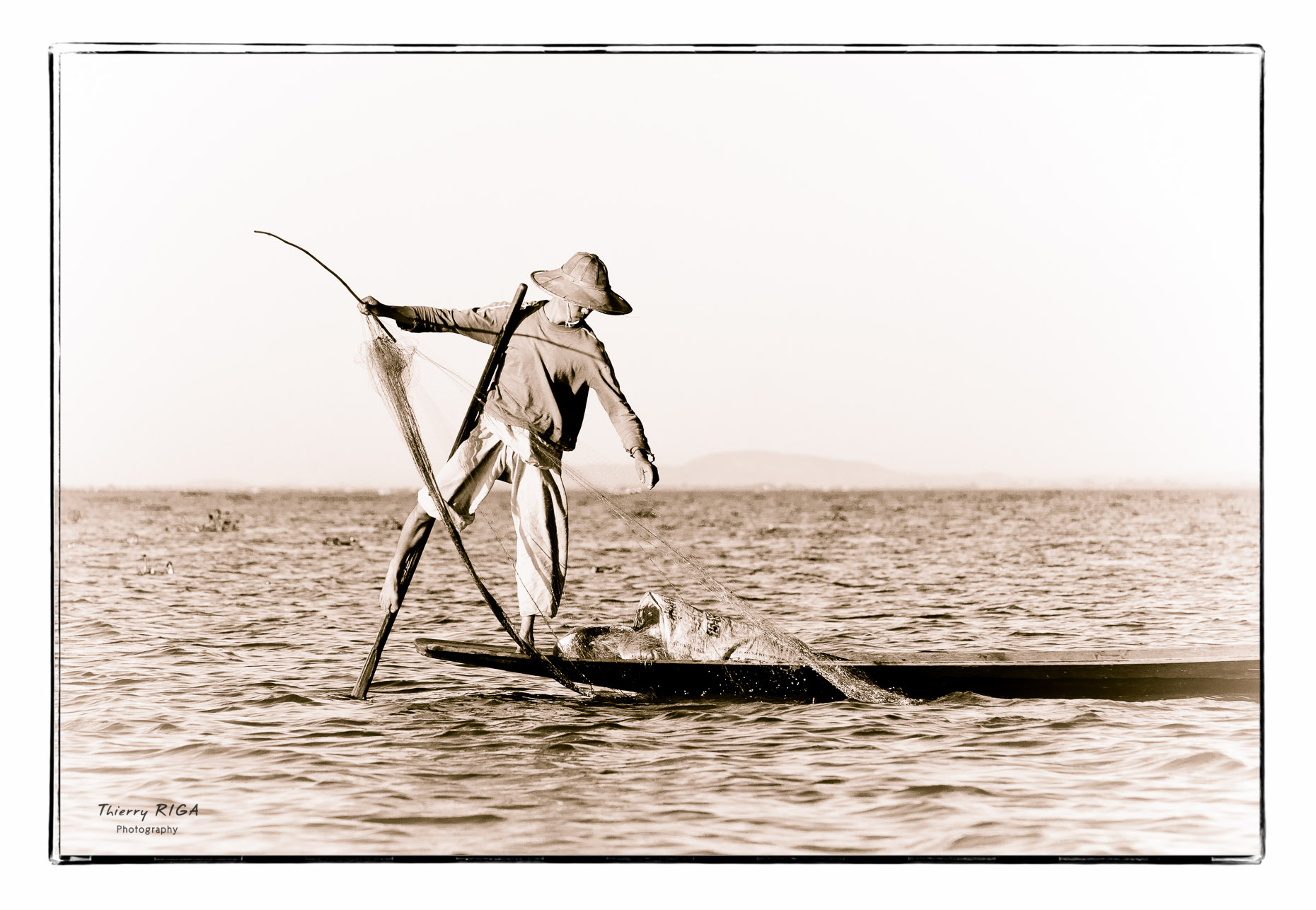 Inlay lake fisherman with hat rowing with his leg, Myanmar