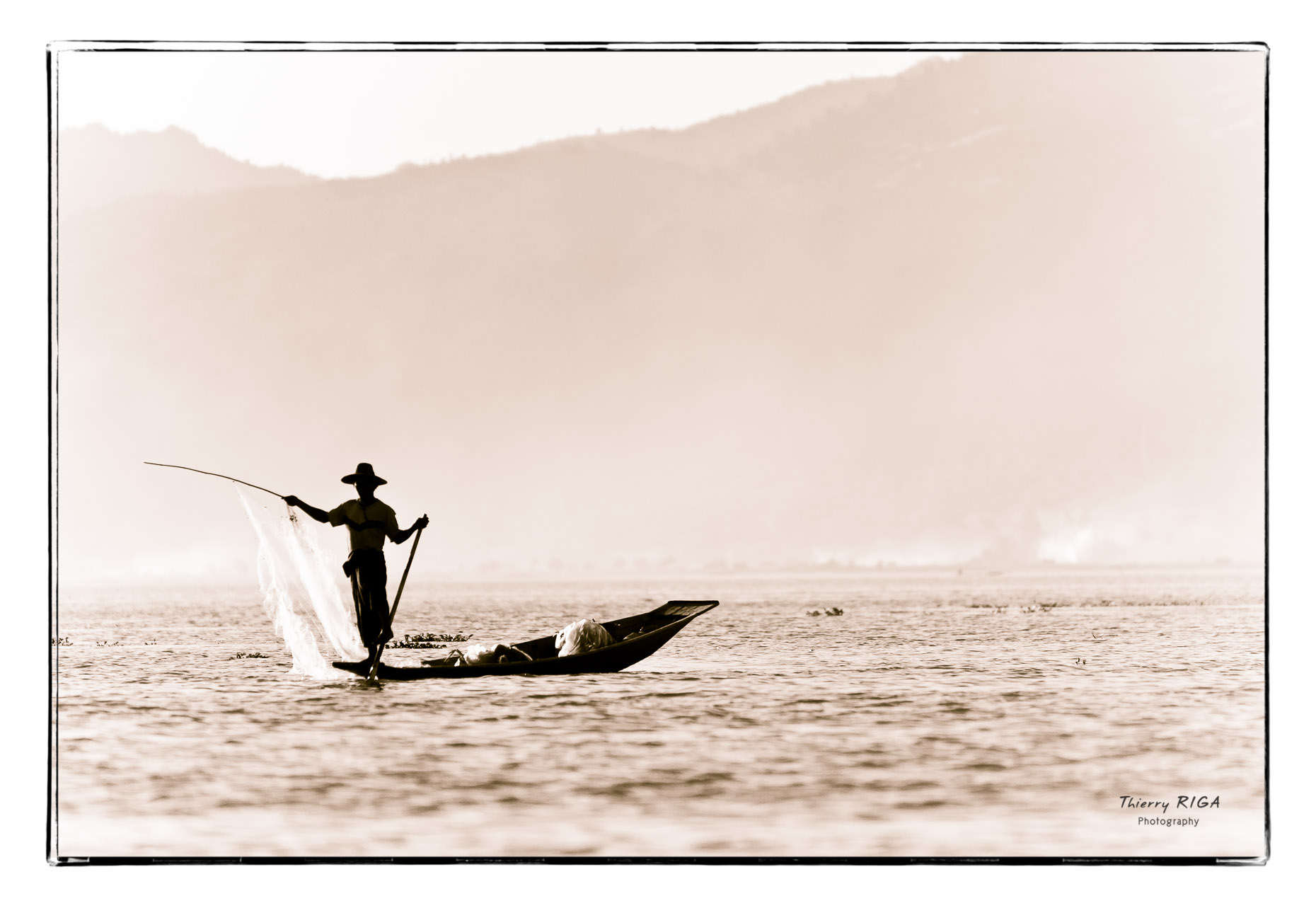 Inlay lake fisherman and his net with mountains in the background, Myanmar